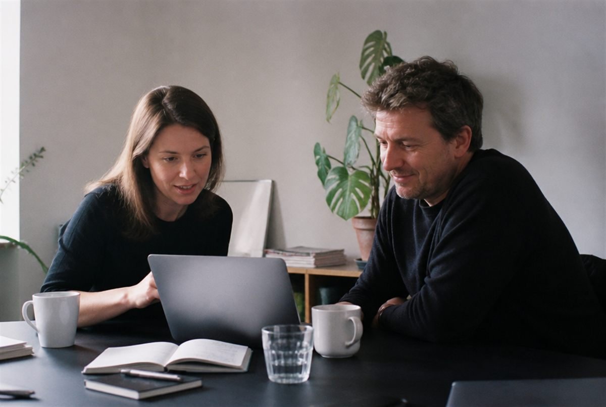 A marketing team and a small business owner meeting at a table, going through a monthly performance report