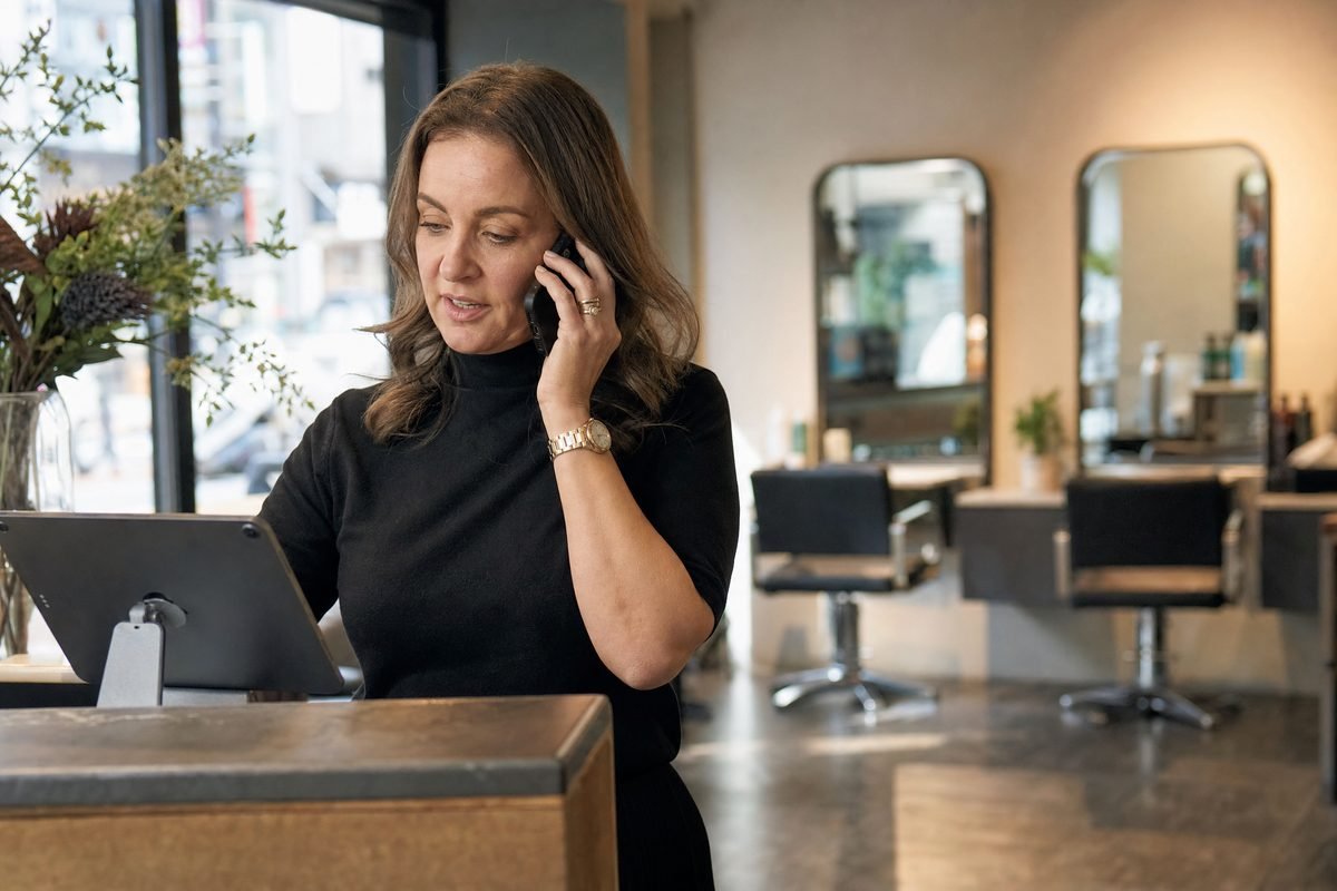 Owner of a small hair salon on the phone at the reception desk